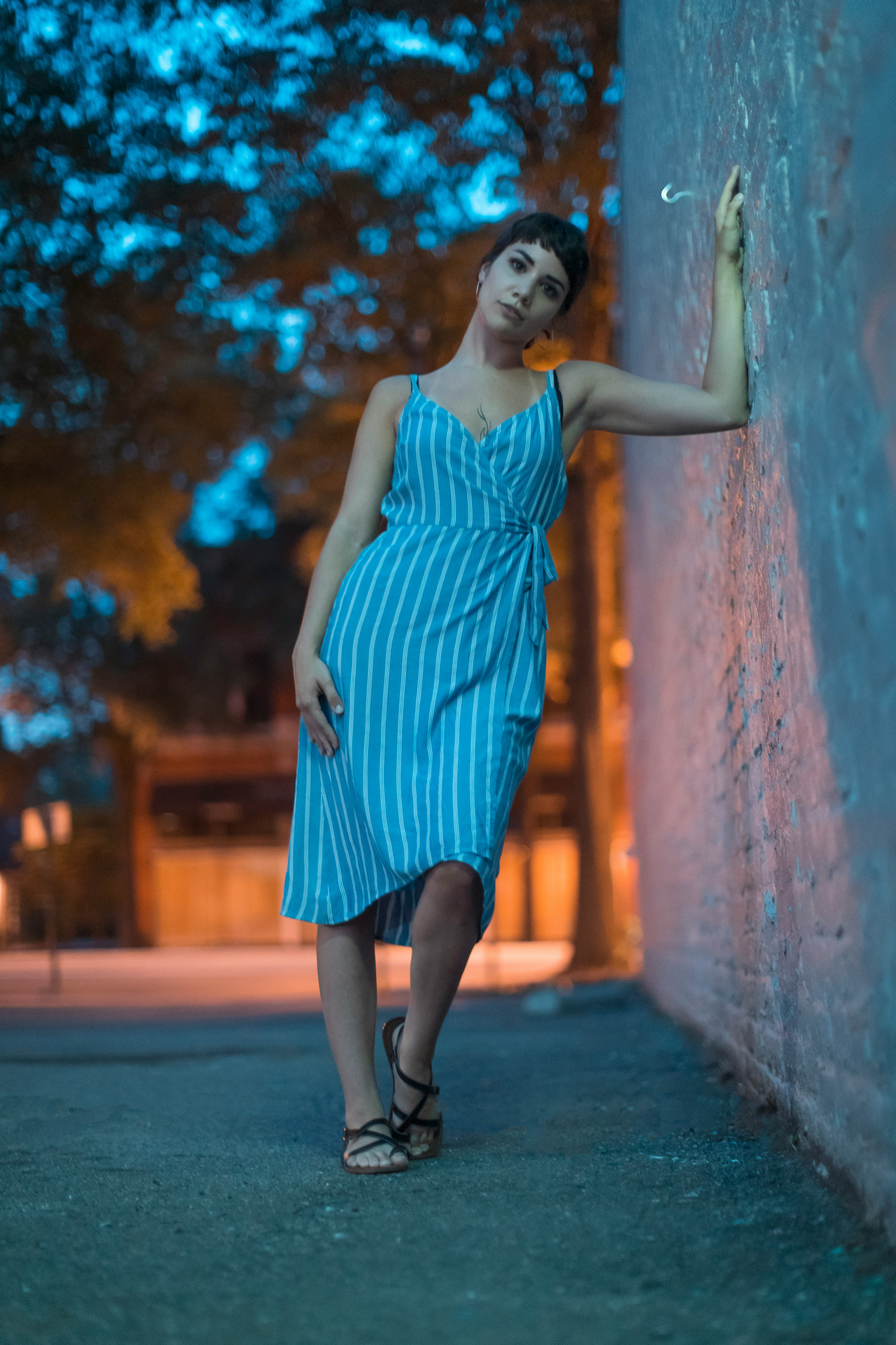 woman in blue sleeveless dress standing on sidewalk during daytime